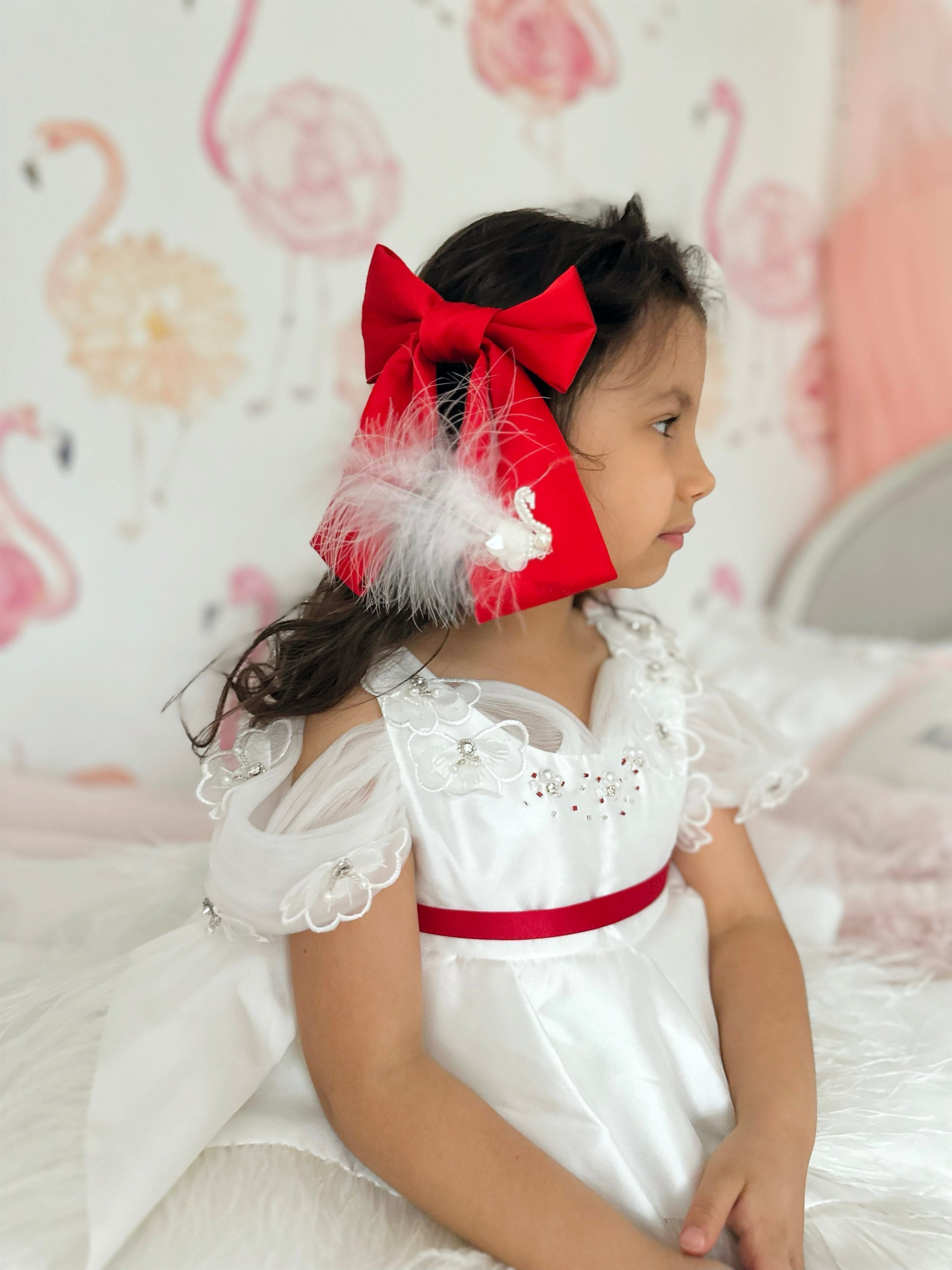 Girl wearing large red satin bow with white feather embellishment
