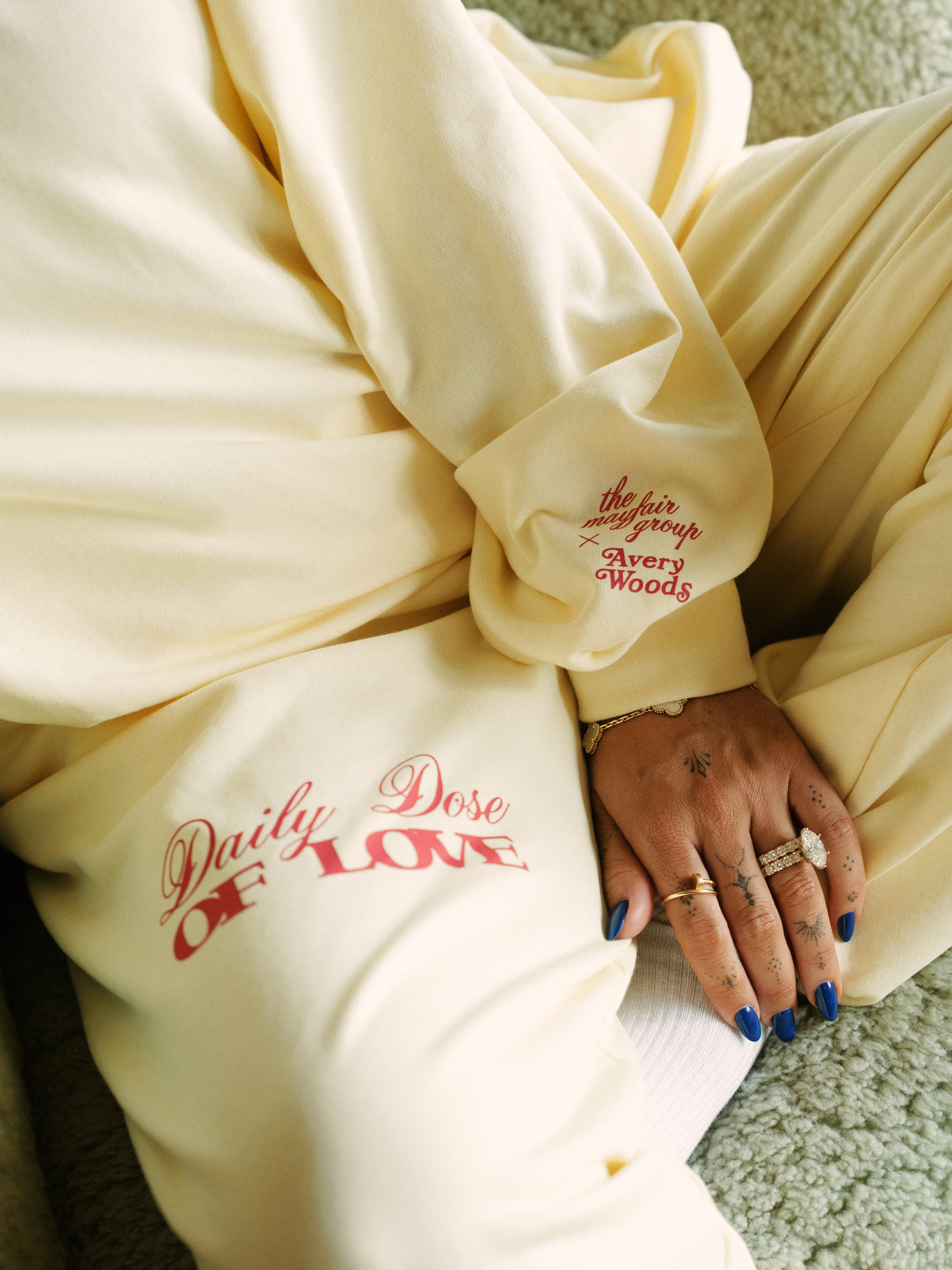 Person wearing a buttercream-colored outfit with text, sitting on a textured surface.