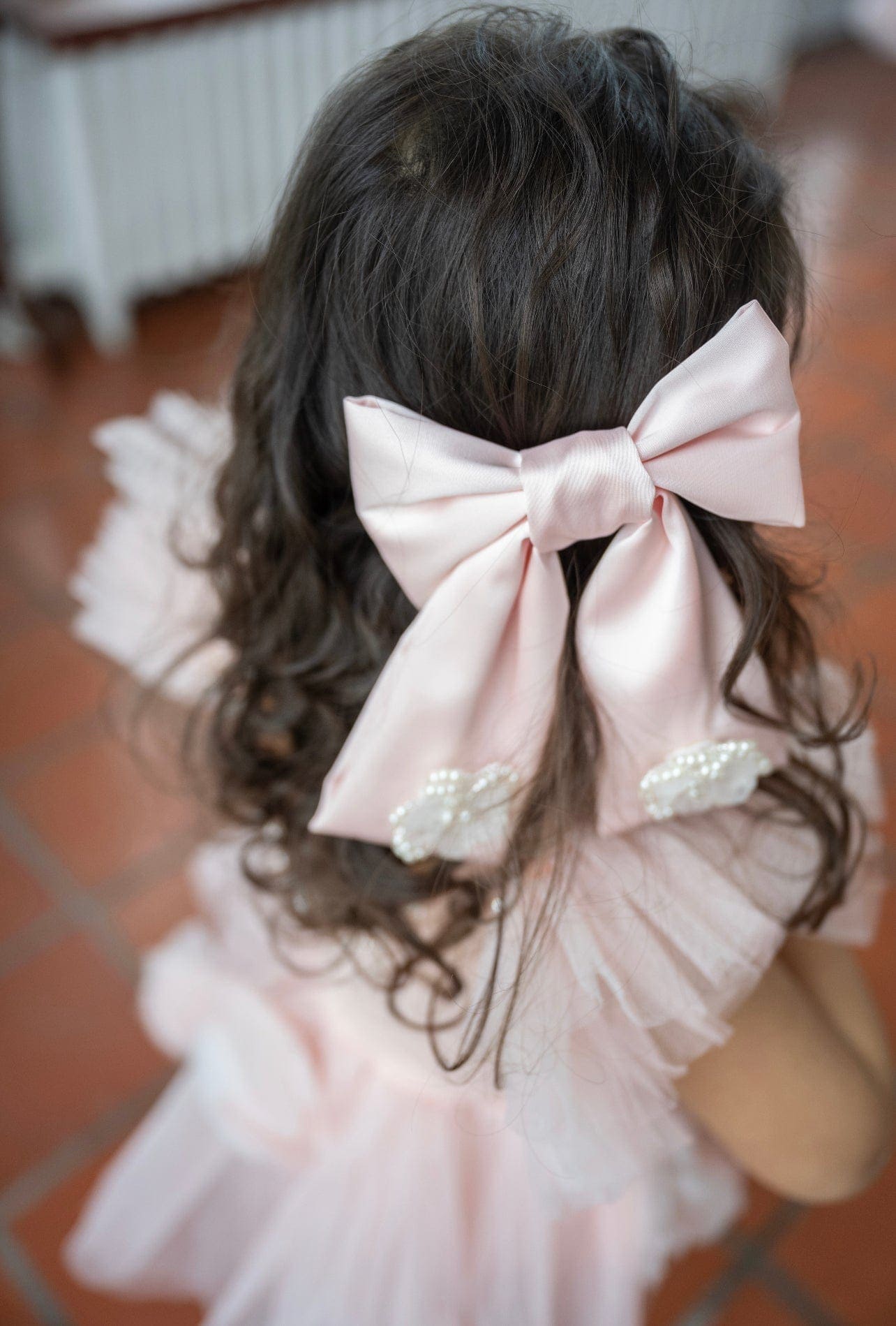Girl wearing large pink satin bow with flower embellishments