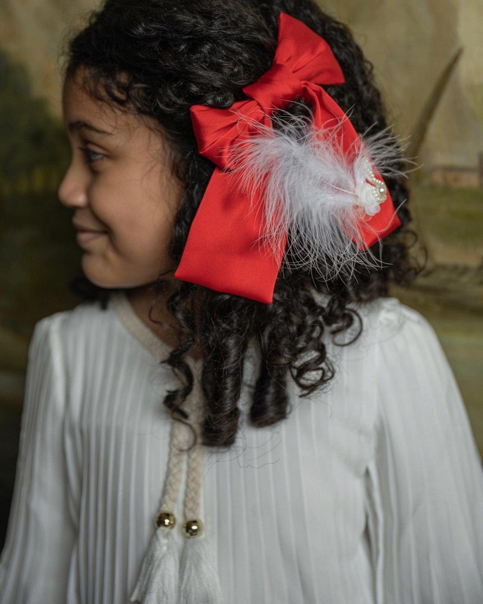 Young girl wearing Red Anise Satin Embroidered Hair Bow with feather accent