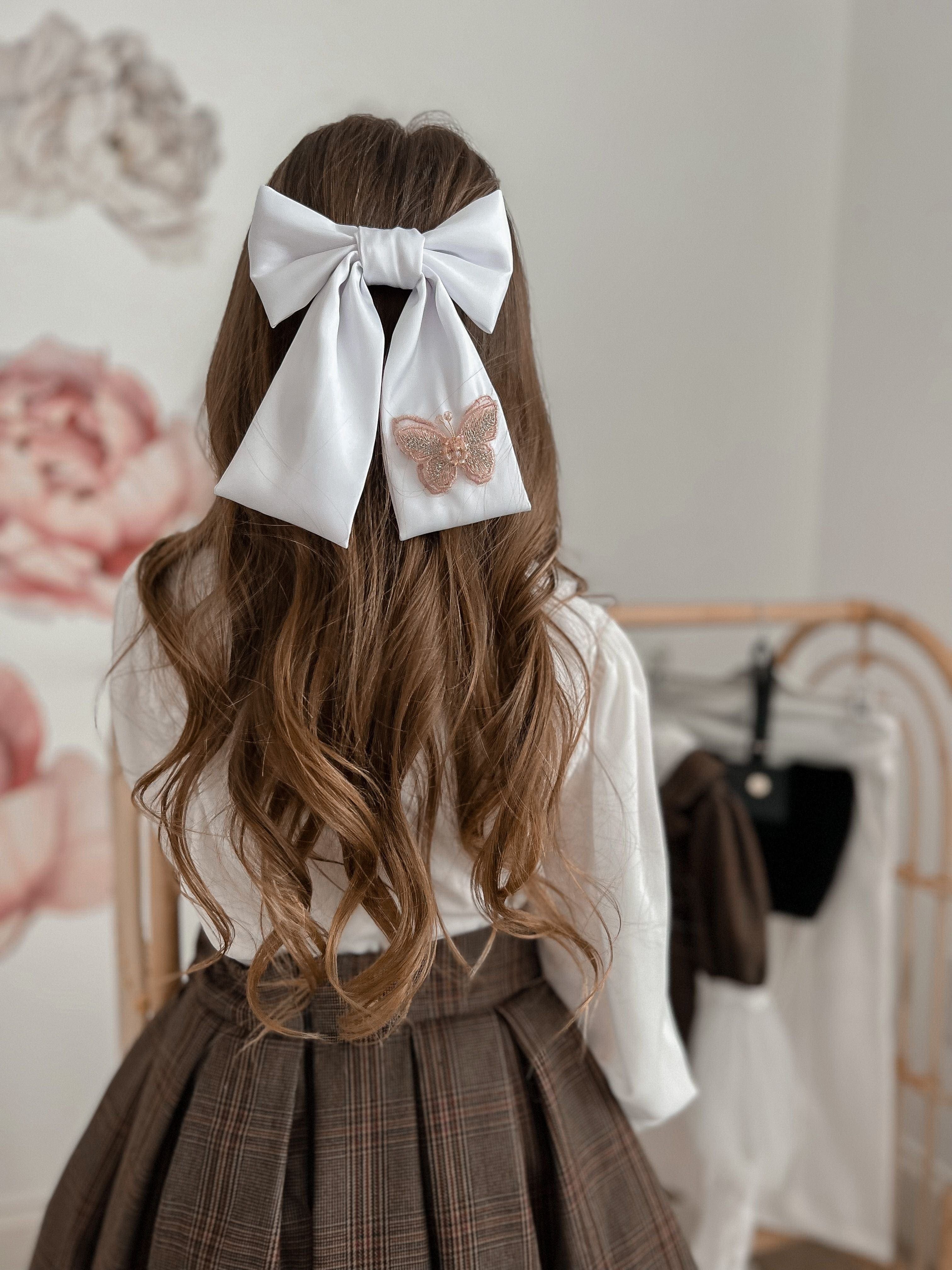 Girl with a large satin bow in her hair embellished with a butterfly detail