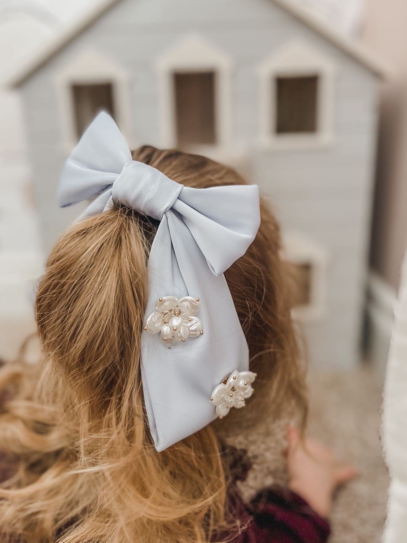 Girl wearing large blue satin hair bow with flower embellishment