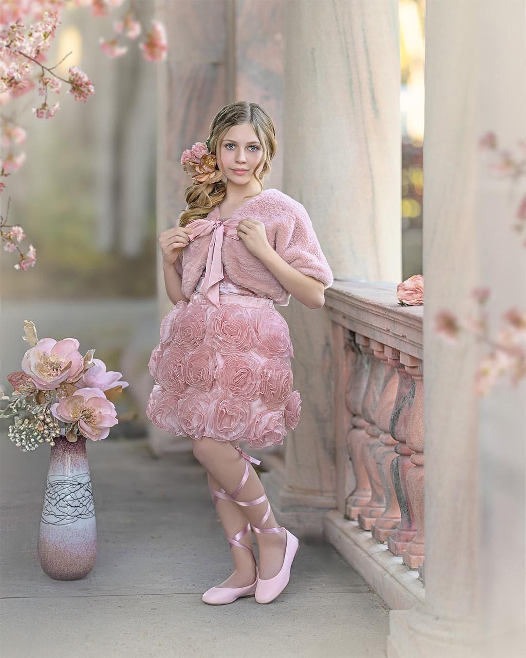 girl in a pink faux fur bolero with a matching floral rose skirt