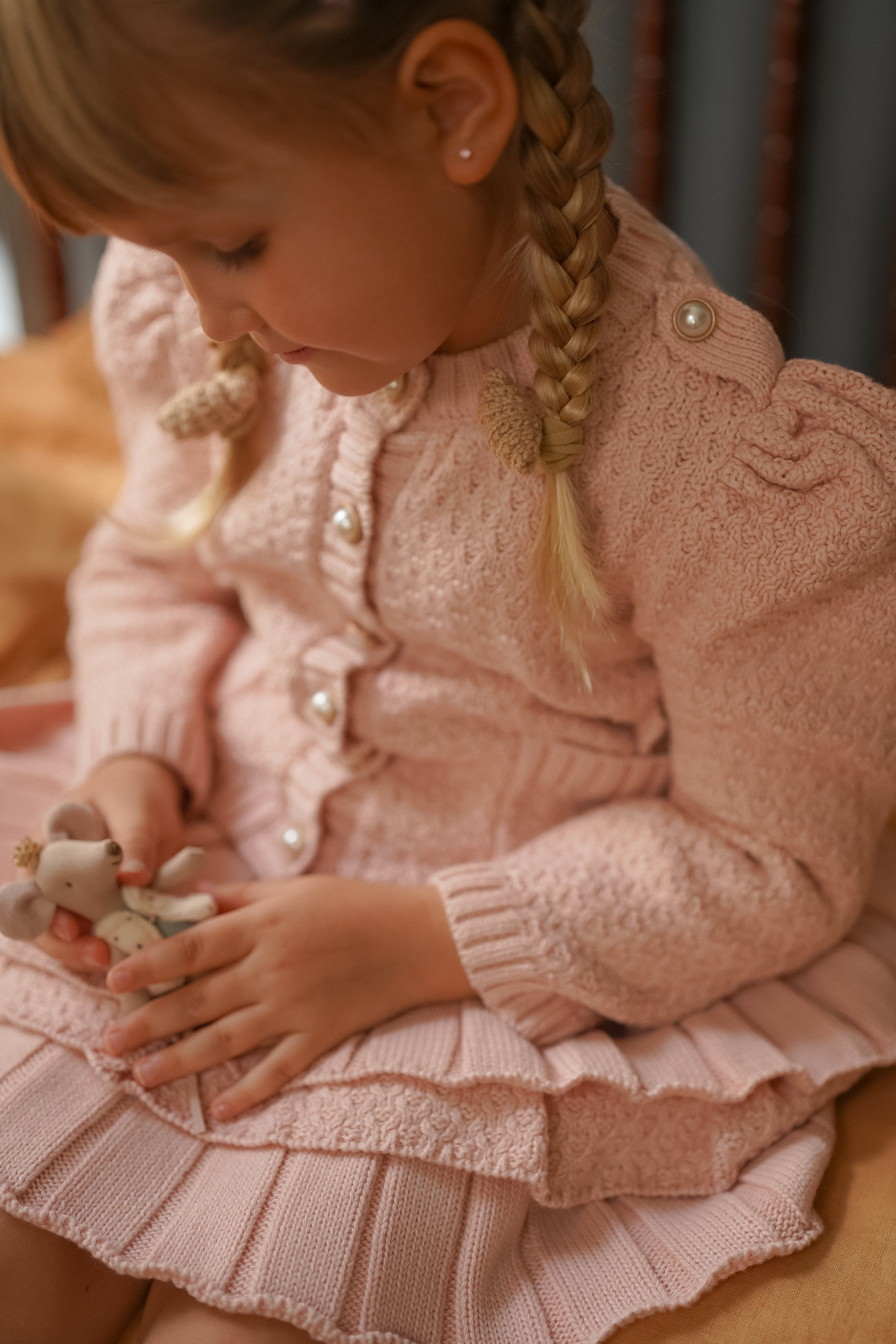 Close up of Julie pink knit cotton cardigan and ruffle skirt showing pearl buttons, puff sleeves and soft knit texture