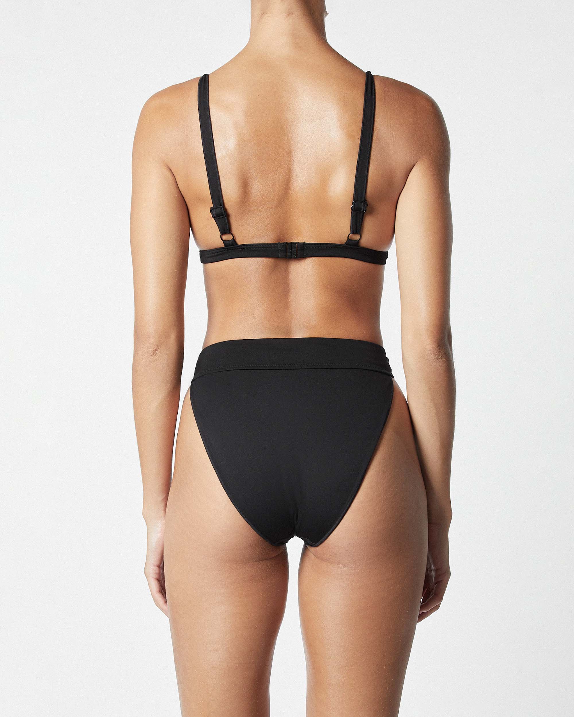 Studio image of model wearing the contour bikini top in black, showcasing its adjustable shoulder straps and clip back design. 