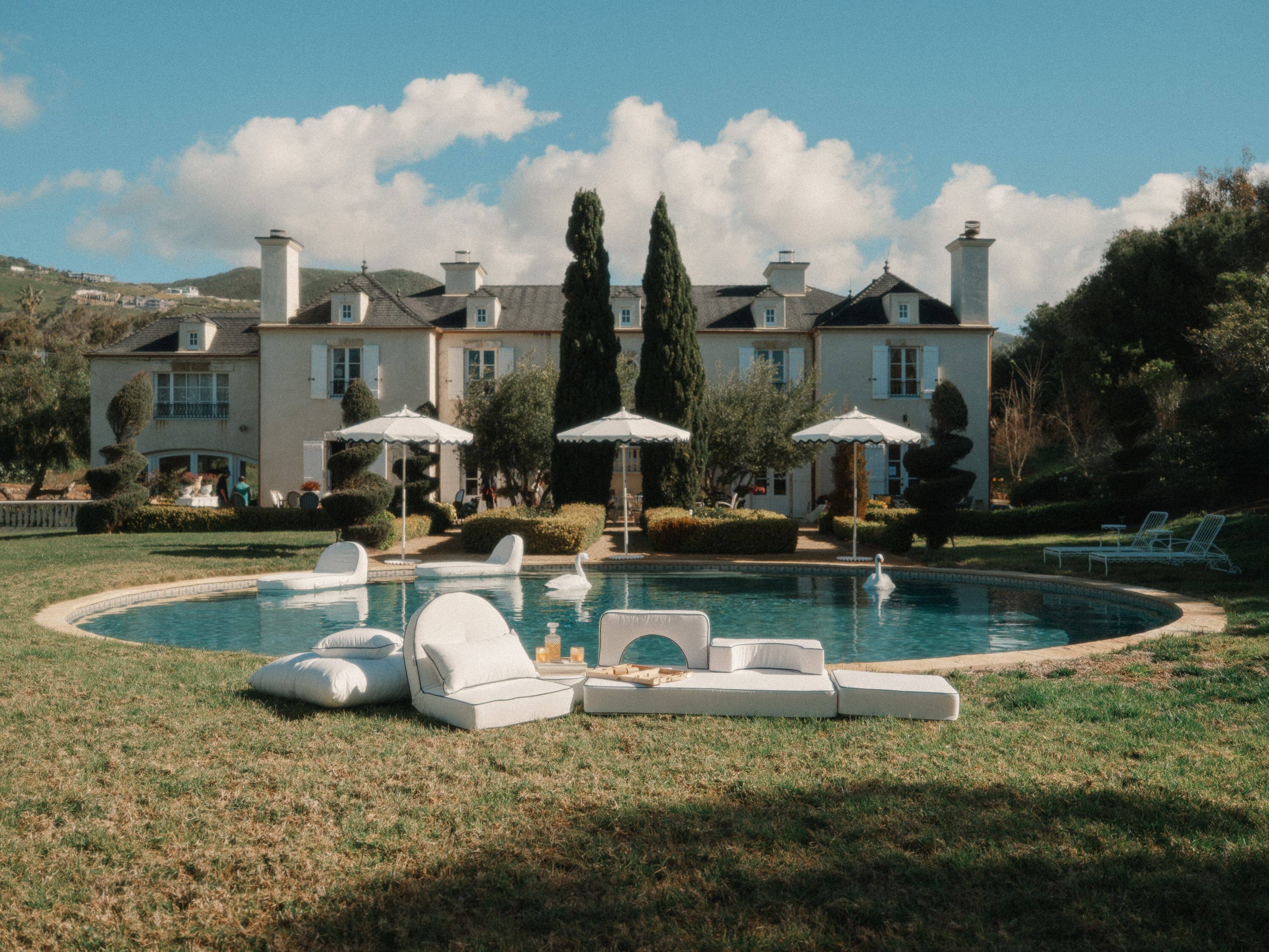 white reclining lounger by the pool with white pillows and cushions